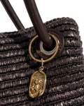 Gold BagBit - Nahaufnahme einer dunkelbraunen, strukturierten Tasche, verziert mit einem ovalen, goldenen Anhänger, der einen kleinen Teddybären in einem strukturierten Relief zeigt.