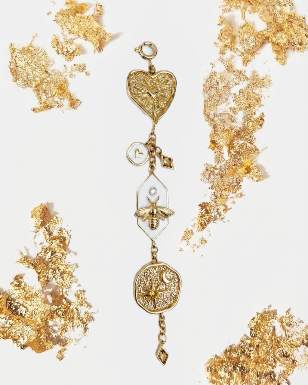 Gold Bag Charm - Mehrteiliger goldener Taschenanhänger mit Herz, Motte und Medaillon, umgeben von goldenen Blattgold-Akzenten.
