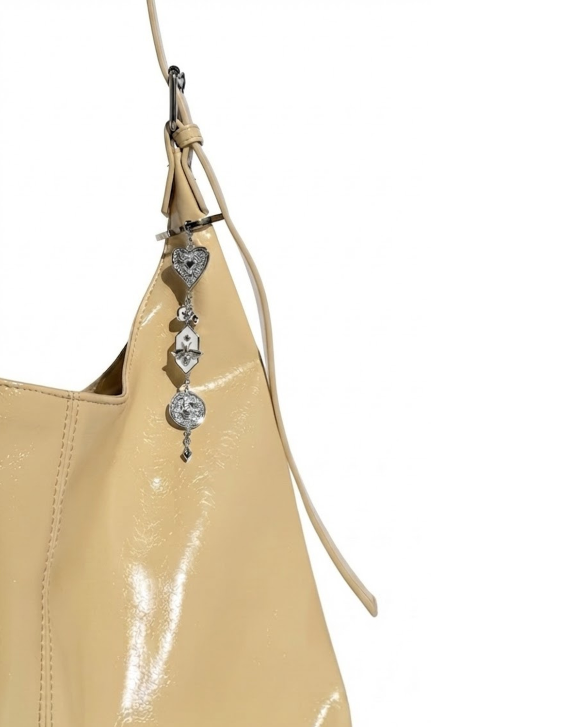 Silber Bag Charm - Aufnahme einer gelben Handtasche mit einem herabhängenden, mehrteiligen Silberanhänger, bestehend aus einem Herz, einer Motte auf weißem Emaille und einem runden Medaillon.