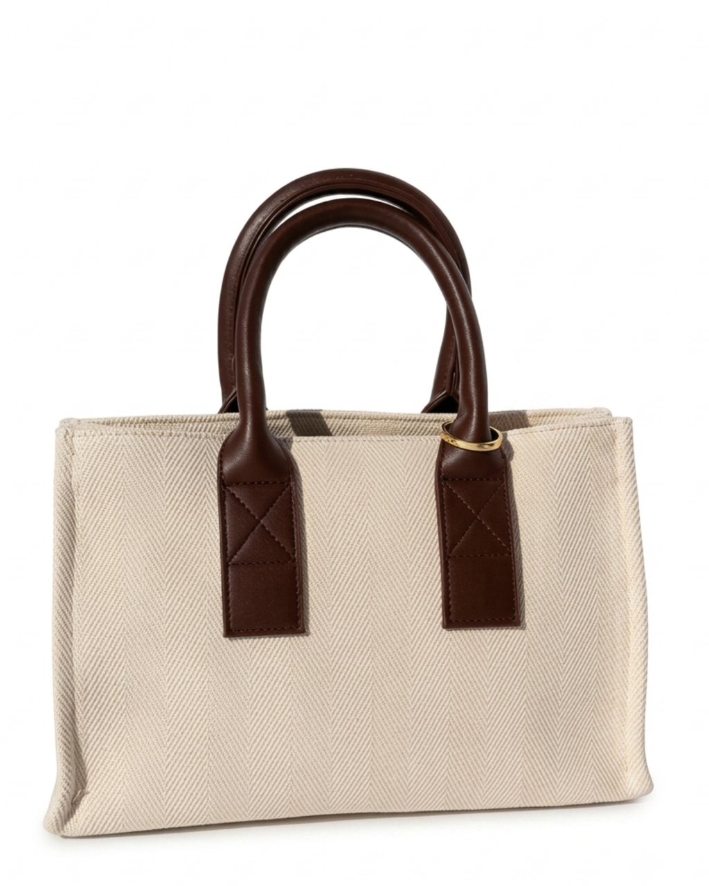 Gold Bag Clip - Aufnahme einer beigefarbenen Canvas-Tasche mit Griffen aus dunkelbraunem Leder, geschmückt mit einem goldenen Metallring.