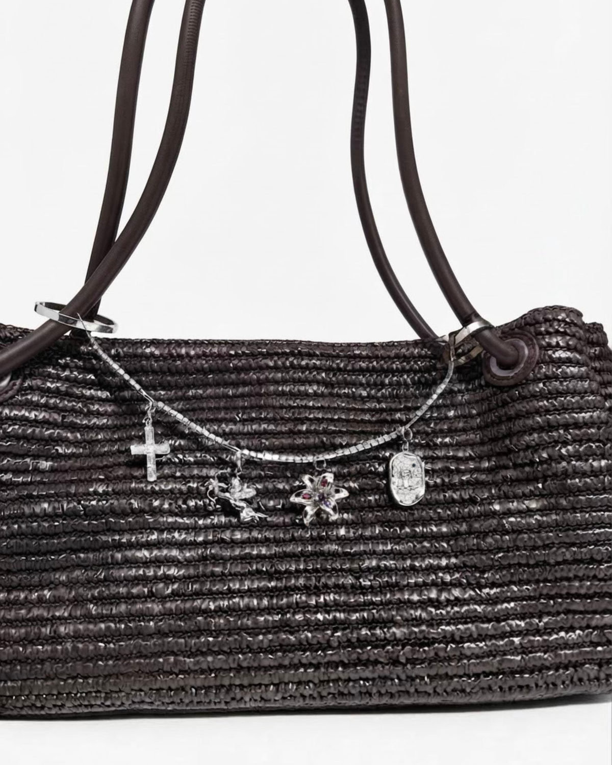 Silber Strass Bag Chain - Dunkelbraune Schultertasche in Flechtoptik mit einer silberfarbene Strasskette zwischen den Taschenhenkeln, verziert mit vier goldenen Anhängern (Motive: Kreuz, Engel, Blume und Teddybär-Medaillon).