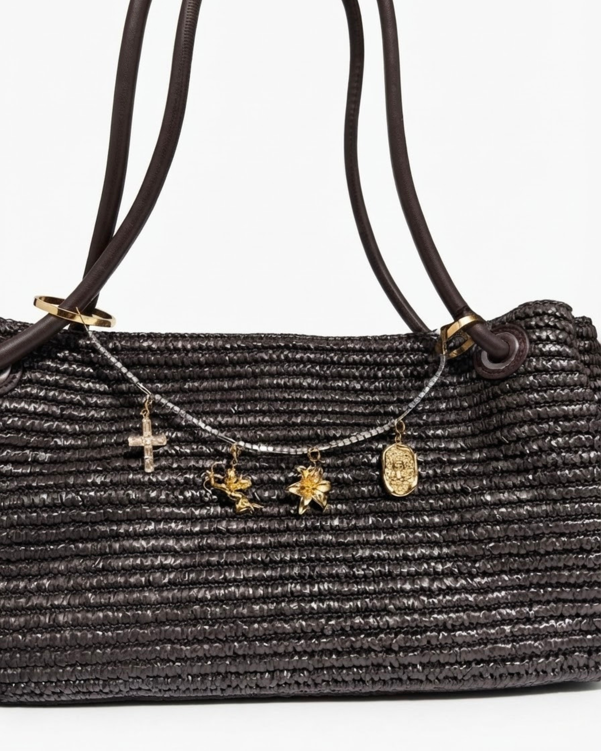 Gold Strass Bag Chain - Dunkelbraune Schultertasche in Flechtoptik mit einer goldfarbenen Strasskette zwischen den Taschenhenkeln, verziert mit vier goldenen Anhängern (Motive: Kreuz, Engel, Blume und Teddybär-Medaillon).
