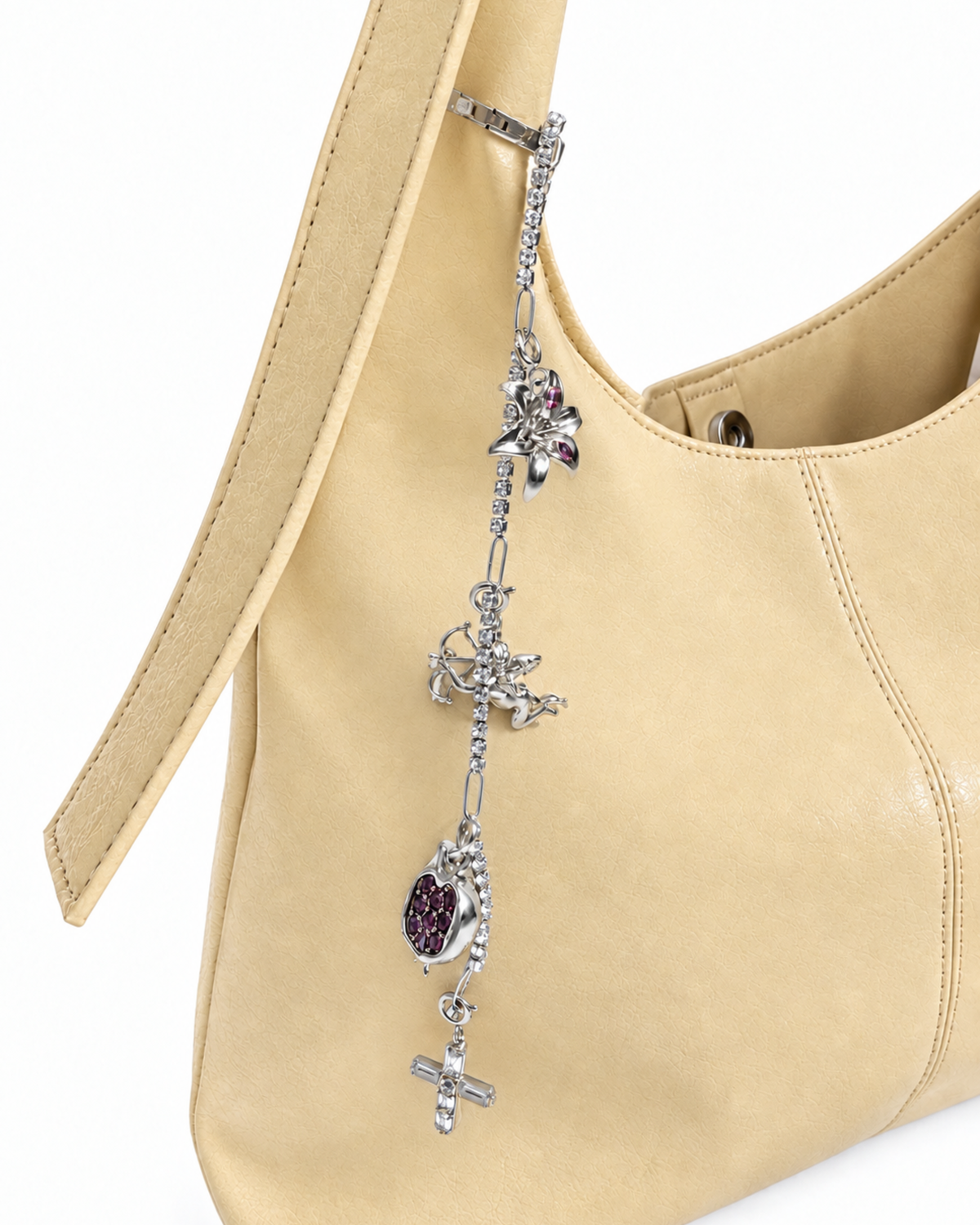 Silber Strass Single Chain - Hellgelbe Leder-Schultertasche mit einer herabhängenden Strasskette am Henkel, verziert mit silbernen Anhängern (Motive: Blume, Engel, Granatapfel und Kreuz).