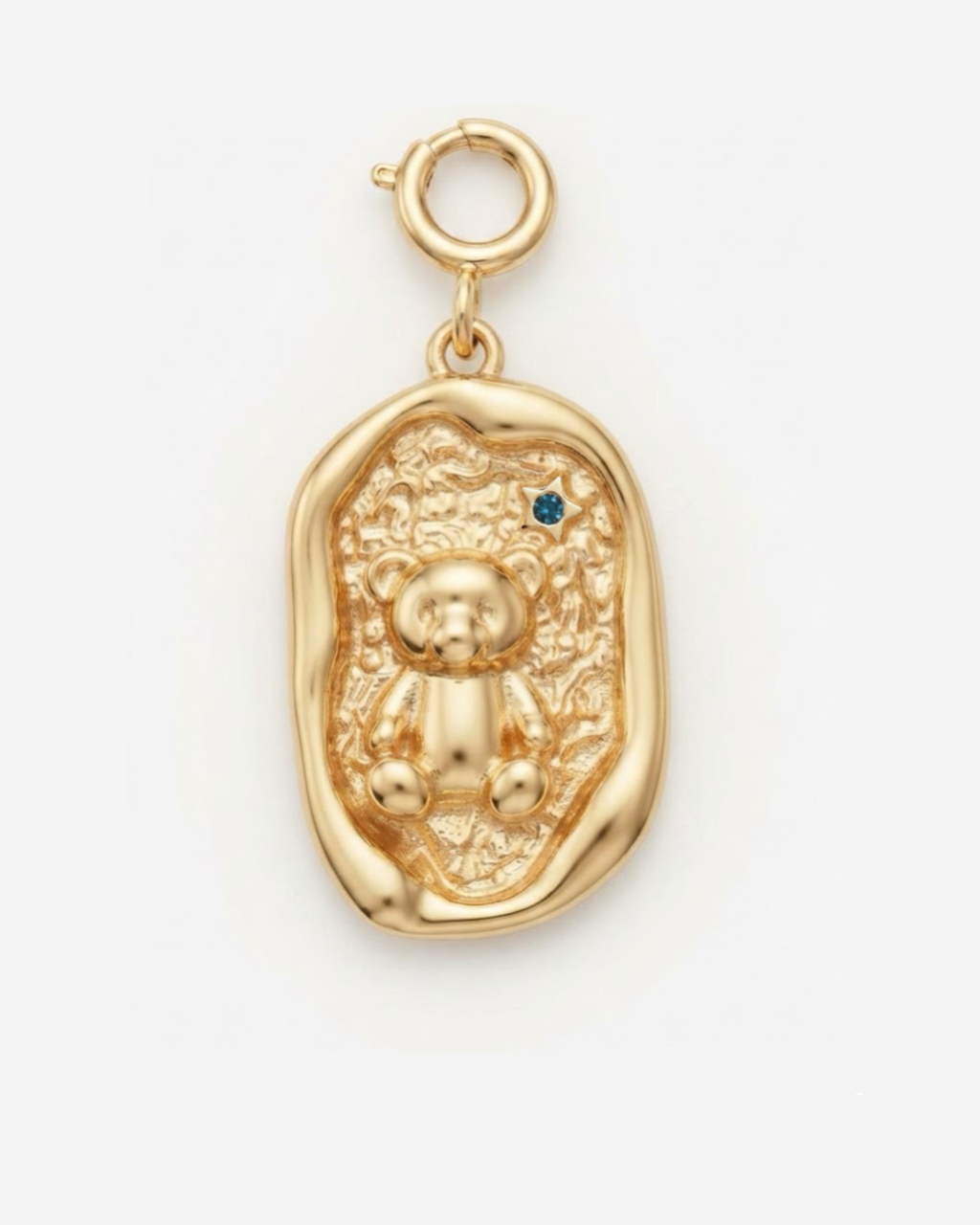 Gold BagBit - Goldener, ovaler Medaillon-Anhänger mit unregelmäßigem Rand, in dessen Mitte ein dreidimensionaler Teddybär auf einer strukturierten Oberfläche sitzt, akzentuiert durch einen kleinen blauen Stein. 