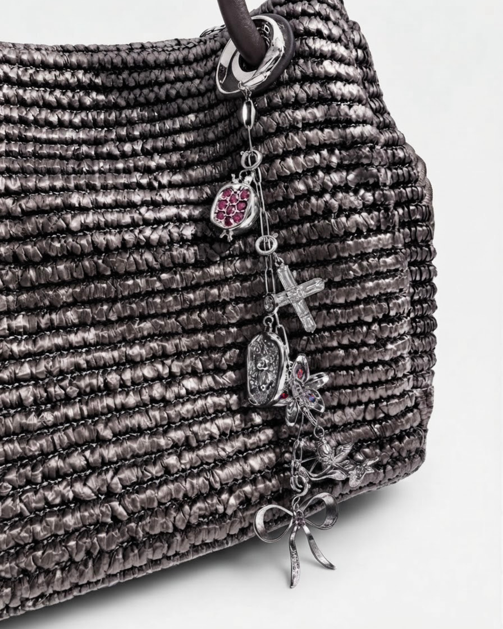 Silber Single Chain - Dunkelbraune Tasche mit einer silberfarbenen Kette am Taschenhenkel, verziert mit silbernen Anhängern wie Granatapfel, Kreuz, Teddybär-Medaillon, Blume, Engel und Schleife.