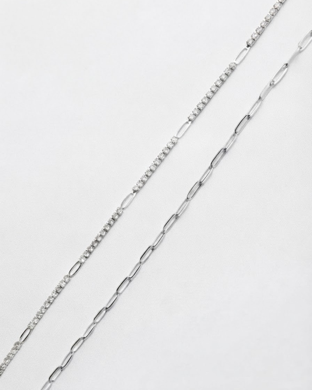 Silber Mixed Duo Chain - Zwei silberfarbene Ketten nebeneinander vor weißem Hintergrund: links eine Kette mit glitzernden Strasssteinen, rechts eine Kette mit länglichen klassischen Gliedern.